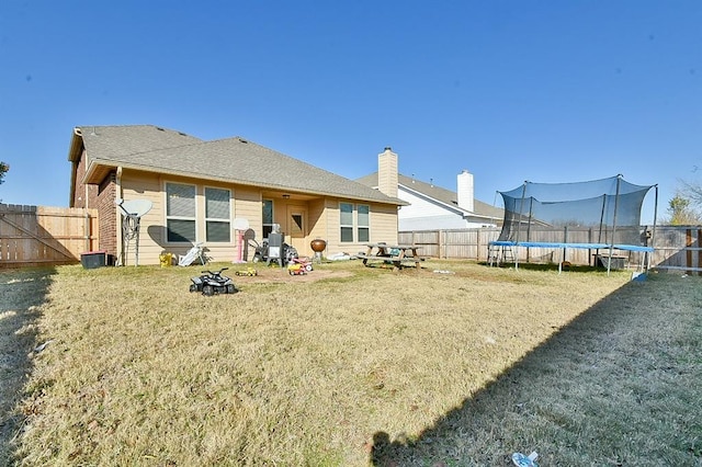 back of property with a yard and a trampoline