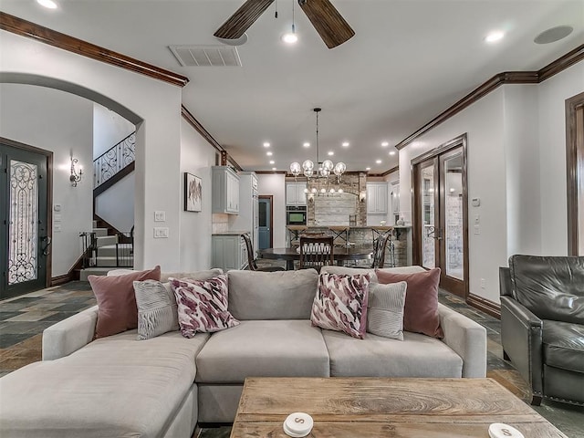 living room with ceiling fan with notable chandelier, crown molding, and french doors