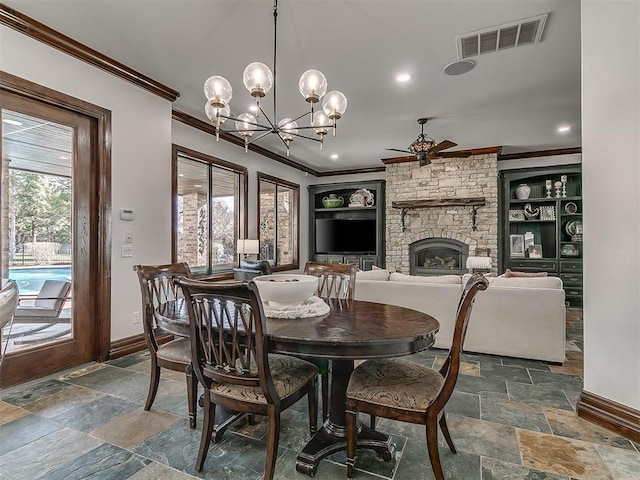 dining space featuring built in features, a stone fireplace, plenty of natural light, and crown molding