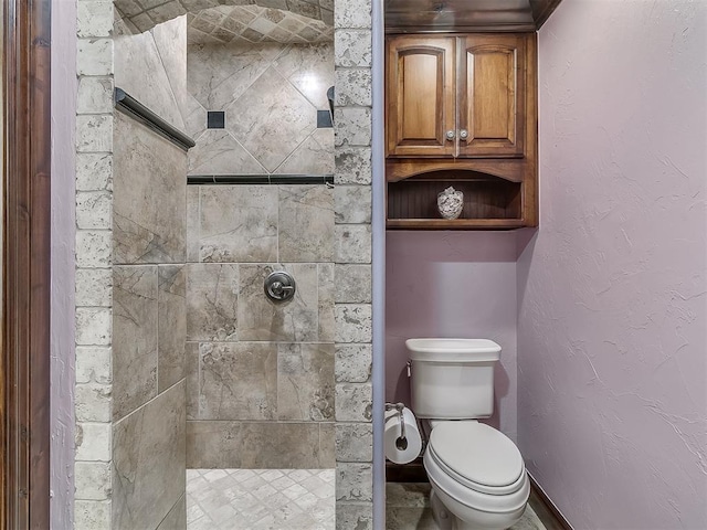 bathroom featuring toilet and a tile shower