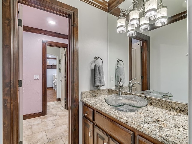 bathroom featuring vanity, ornamental molding, and an inviting chandelier