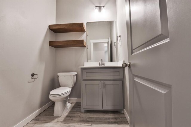 bathroom with hardwood / wood-style floors, vanity, and toilet