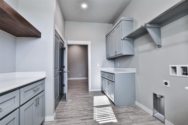 washroom featuring electric dryer hookup, cabinets, hookup for a washing machine, and light hardwood / wood-style flooring