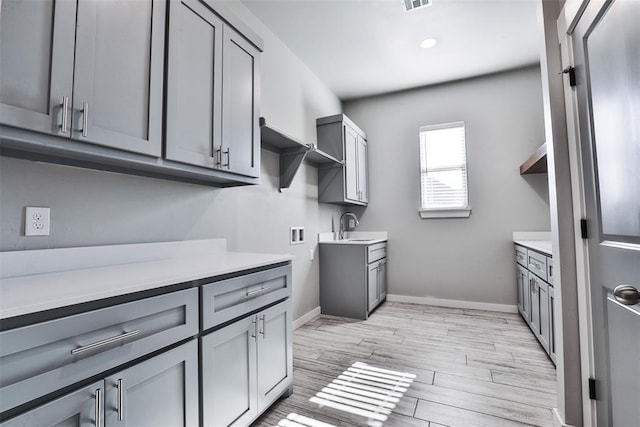 interior space featuring cabinets, hookup for a washing machine, light hardwood / wood-style floors, and sink