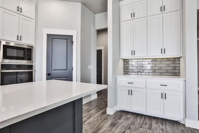 kitchen with white cabinets, dark hardwood / wood-style floors, backsplash, and appliances with stainless steel finishes