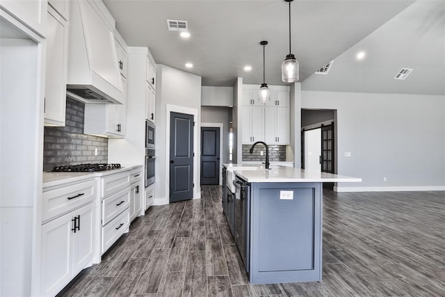 kitchen featuring premium range hood, a kitchen island with sink, decorative light fixtures, white cabinets, and dark hardwood / wood-style floors