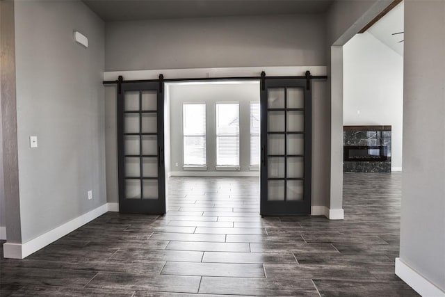 empty room with french doors, a barn door, and dark wood-type flooring