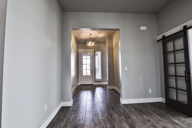 foyer entrance featuring dark hardwood / wood-style floors, a barn door, and a chandelier