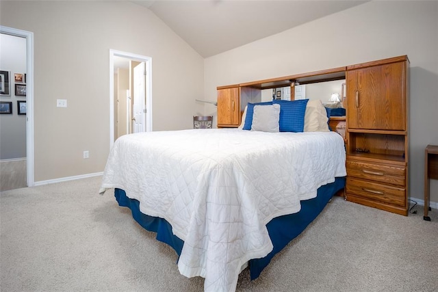 bedroom with light carpet, ensuite bathroom, and lofted ceiling