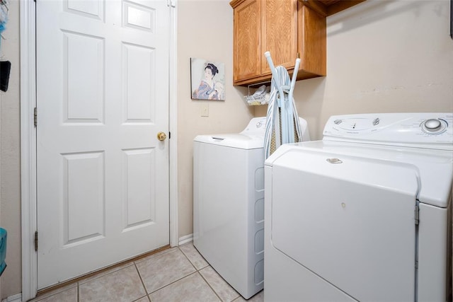 laundry room featuring cabinets, separate washer and dryer, and light tile patterned floors