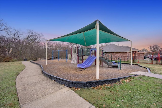 playground at dusk featuring a lawn