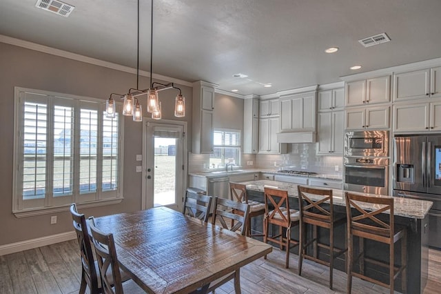 dining area with hardwood / wood-style floors, ornamental molding, and sink