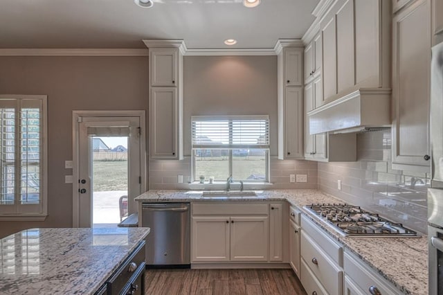 kitchen featuring white cabinetry, light stone counters, stainless steel appliances, and ornamental molding