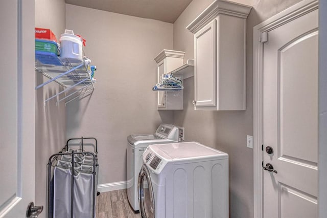 washroom featuring washing machine and clothes dryer, hardwood / wood-style floors, and cabinets