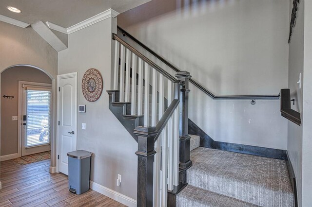 staircase featuring wood-type flooring and crown molding