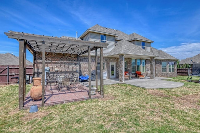 back of house featuring a lawn, a pergola, a trampoline, and a patio