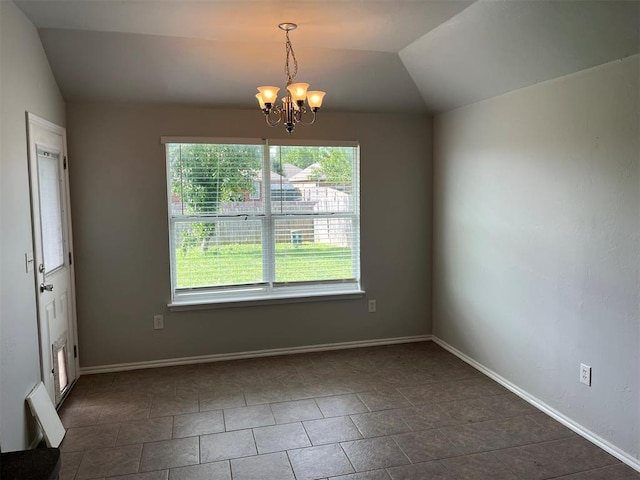 empty room featuring dark tile patterned flooring, a chandelier, and vaulted ceiling