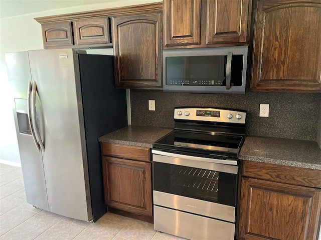 kitchen featuring decorative backsplash, light tile patterned flooring, dark brown cabinetry, and stainless steel appliances