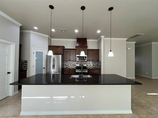 kitchen featuring dark stone countertops, sink, a center island with sink, and appliances with stainless steel finishes