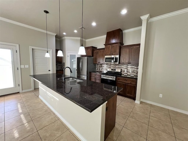 kitchen with stainless steel appliances, a center island with sink, dark stone counters, and sink