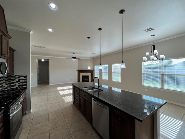 kitchen featuring sink, stainless steel appliances, dark stone counters, pendant lighting, and ceiling fan with notable chandelier