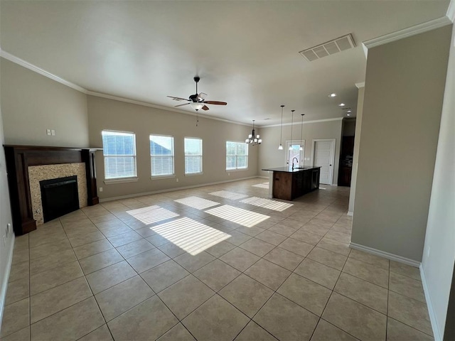 unfurnished living room with ceiling fan with notable chandelier, sink, light tile patterned floors, and crown molding