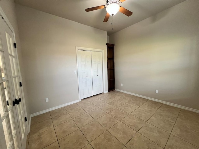 unfurnished bedroom with light tile patterned floors, a closet, and ceiling fan