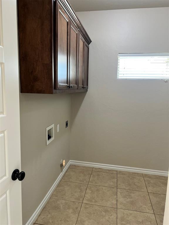 washroom with hookup for an electric dryer, light tile patterned flooring, cabinets, and hookup for a washing machine