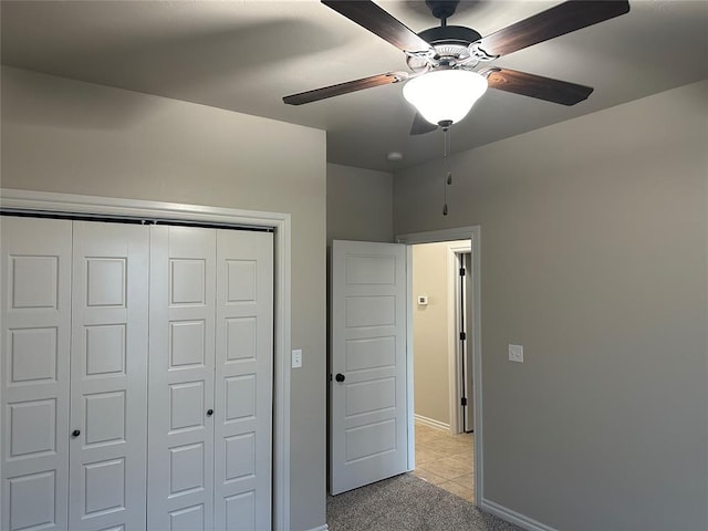 unfurnished bedroom featuring light carpet, a closet, and ceiling fan