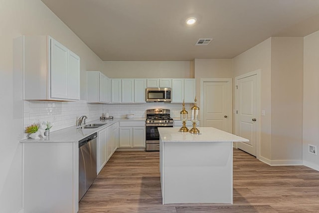 kitchen with a center island, sink, appliances with stainless steel finishes, white cabinets, and light wood-type flooring