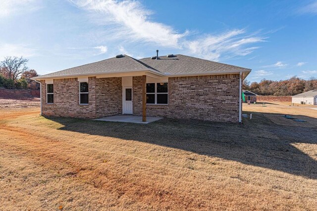 back of property with a yard and a patio