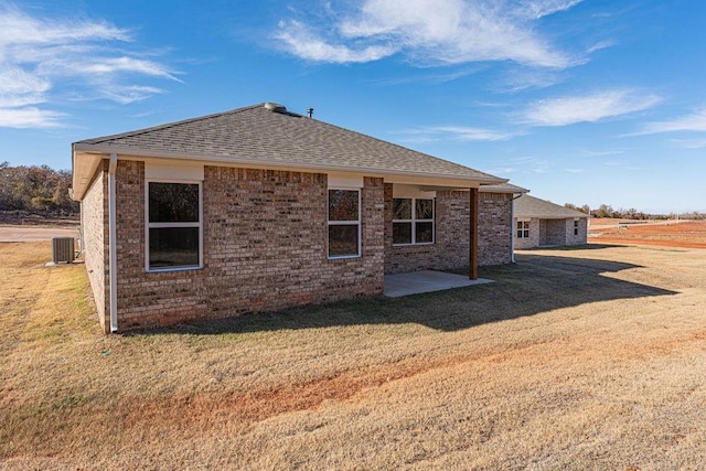 back of property with a lawn, central AC, and a patio area