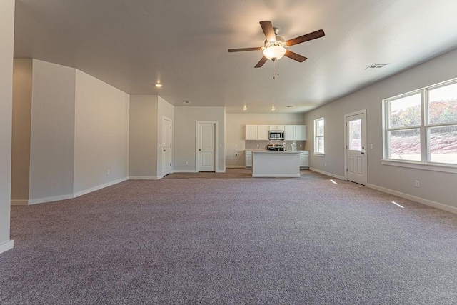 unfurnished living room featuring light carpet and ceiling fan