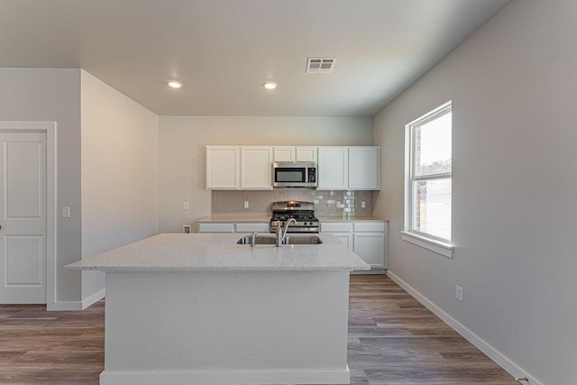 kitchen with sink, white cabinetry, appliances with stainless steel finishes, and a center island with sink