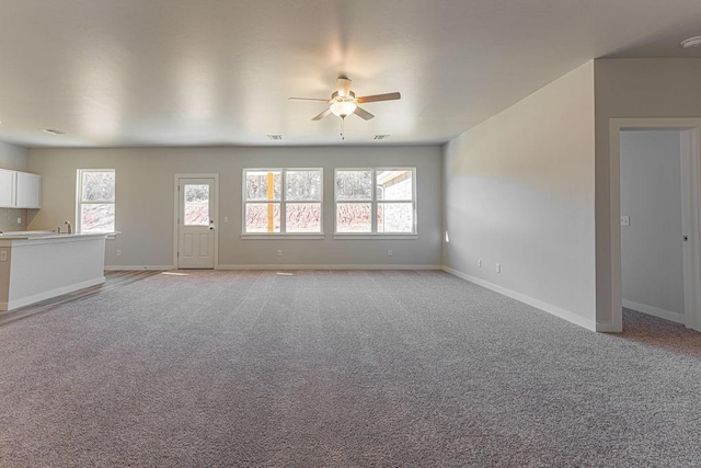 unfurnished living room with ceiling fan, sink, and light carpet