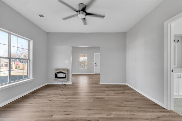 unfurnished living room with a healthy amount of sunlight, light hardwood / wood-style flooring, and heating unit