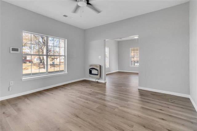 unfurnished living room featuring ceiling fan, wood-type flooring, and heating unit