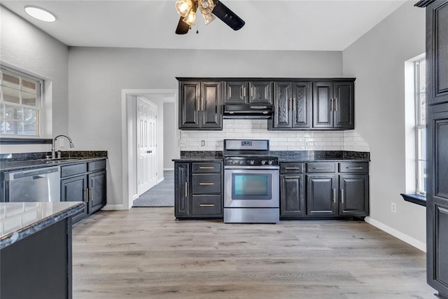 kitchen with light hardwood / wood-style floors, dark stone countertops, appliances with stainless steel finishes, and tasteful backsplash