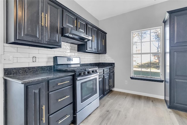 kitchen with gas stove, tasteful backsplash, dark stone counters, and light hardwood / wood-style floors