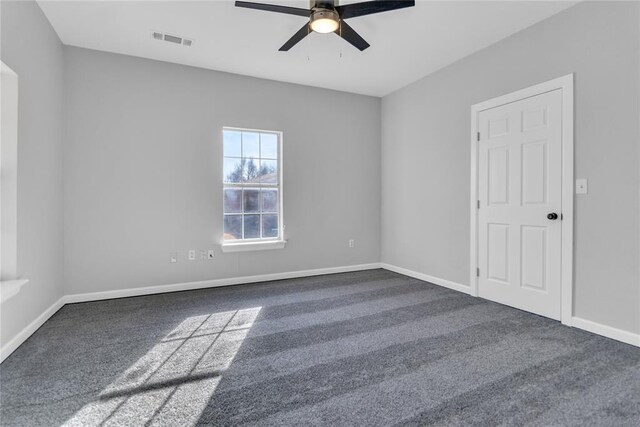 empty room featuring ceiling fan and dark carpet