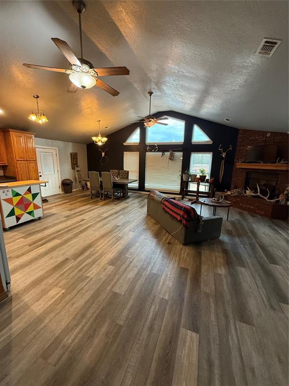 playroom featuring a textured ceiling, ceiling fan with notable chandelier, wood-type flooring, and vaulted ceiling