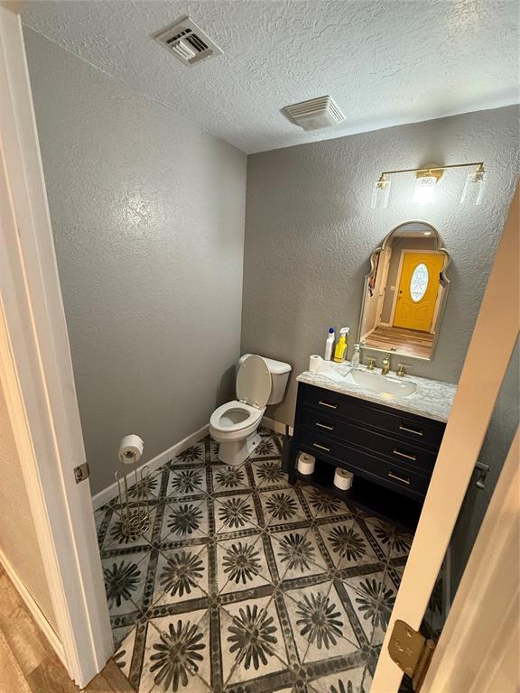 bathroom with vanity, a textured ceiling, and toilet