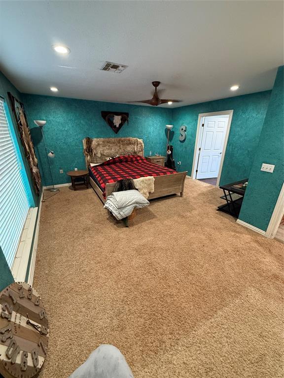 carpeted bedroom featuring multiple windows and ceiling fan