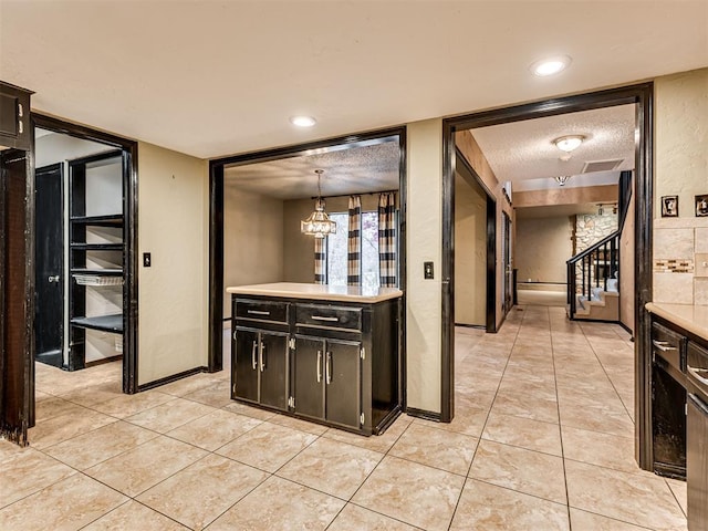 kitchen with light tile patterned floors, hanging light fixtures, a textured ceiling, and an inviting chandelier