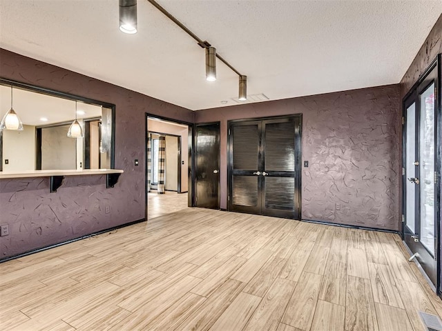 spare room with french doors, a textured ceiling, and light hardwood / wood-style flooring