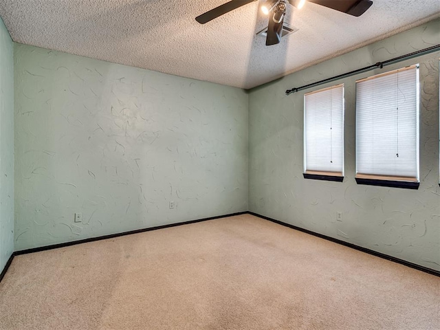 empty room with ceiling fan, light colored carpet, and a textured ceiling