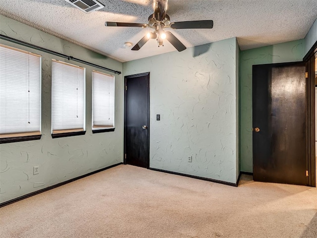 unfurnished bedroom with a textured ceiling, light colored carpet, and ceiling fan