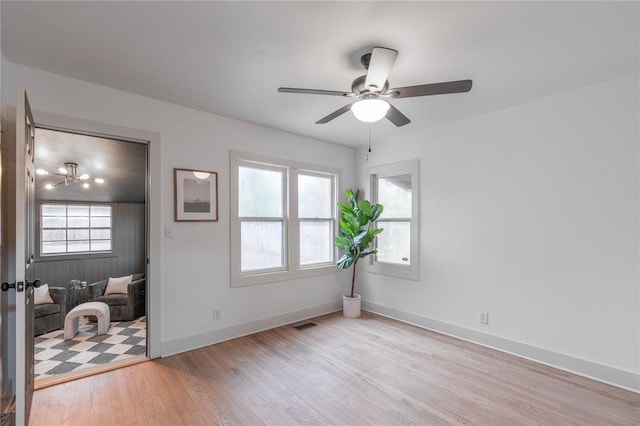 bedroom with ceiling fan with notable chandelier and light hardwood / wood-style flooring