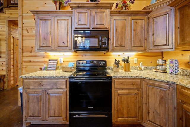 kitchen featuring light stone counters, wooden walls, and black appliances