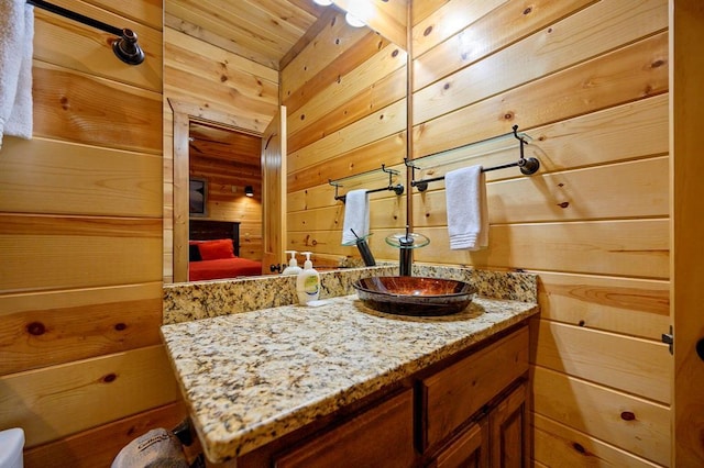 bathroom featuring vanity and wood walls